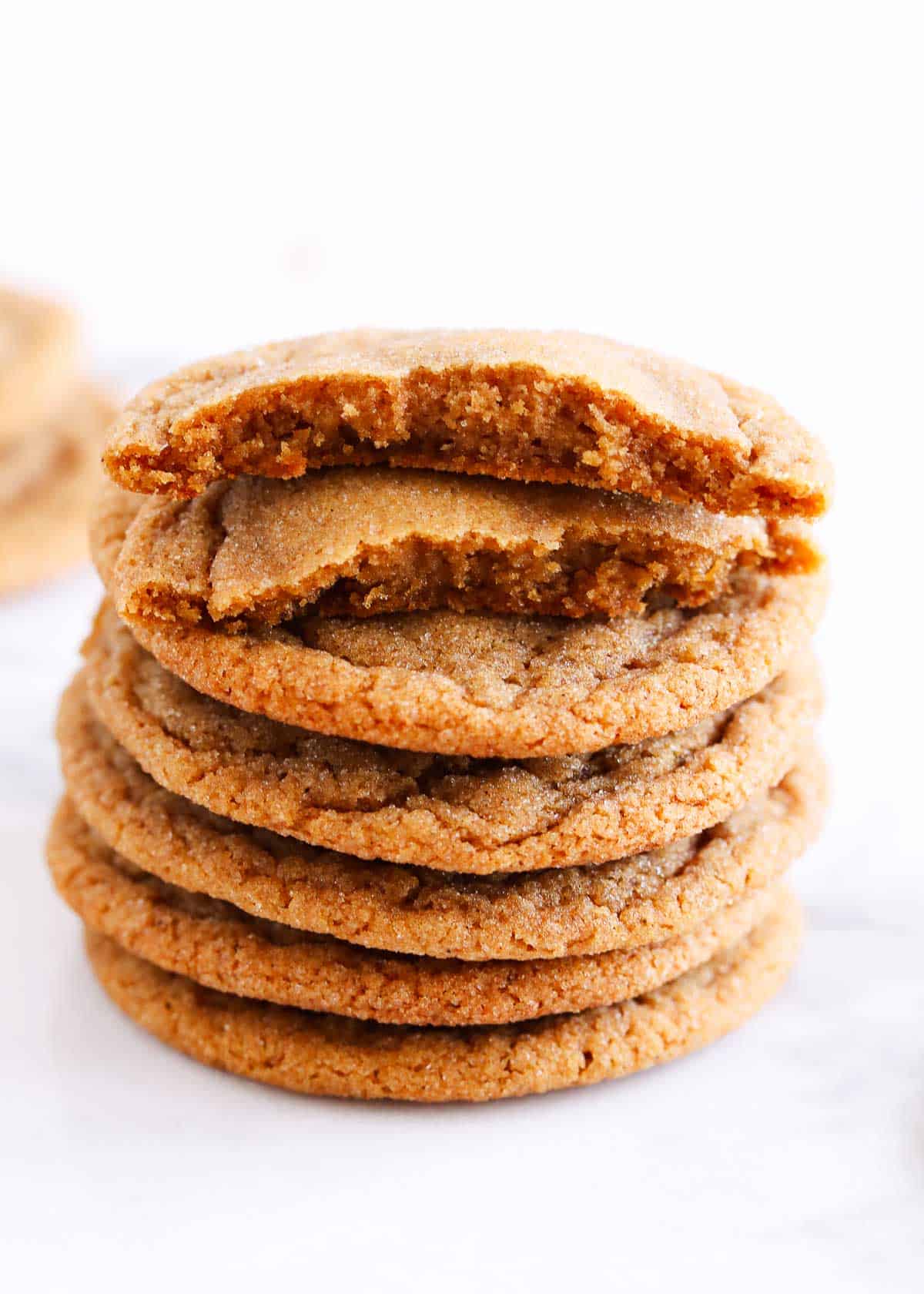 Stack of molasses cookies with the top cookie has a bite out of it. 