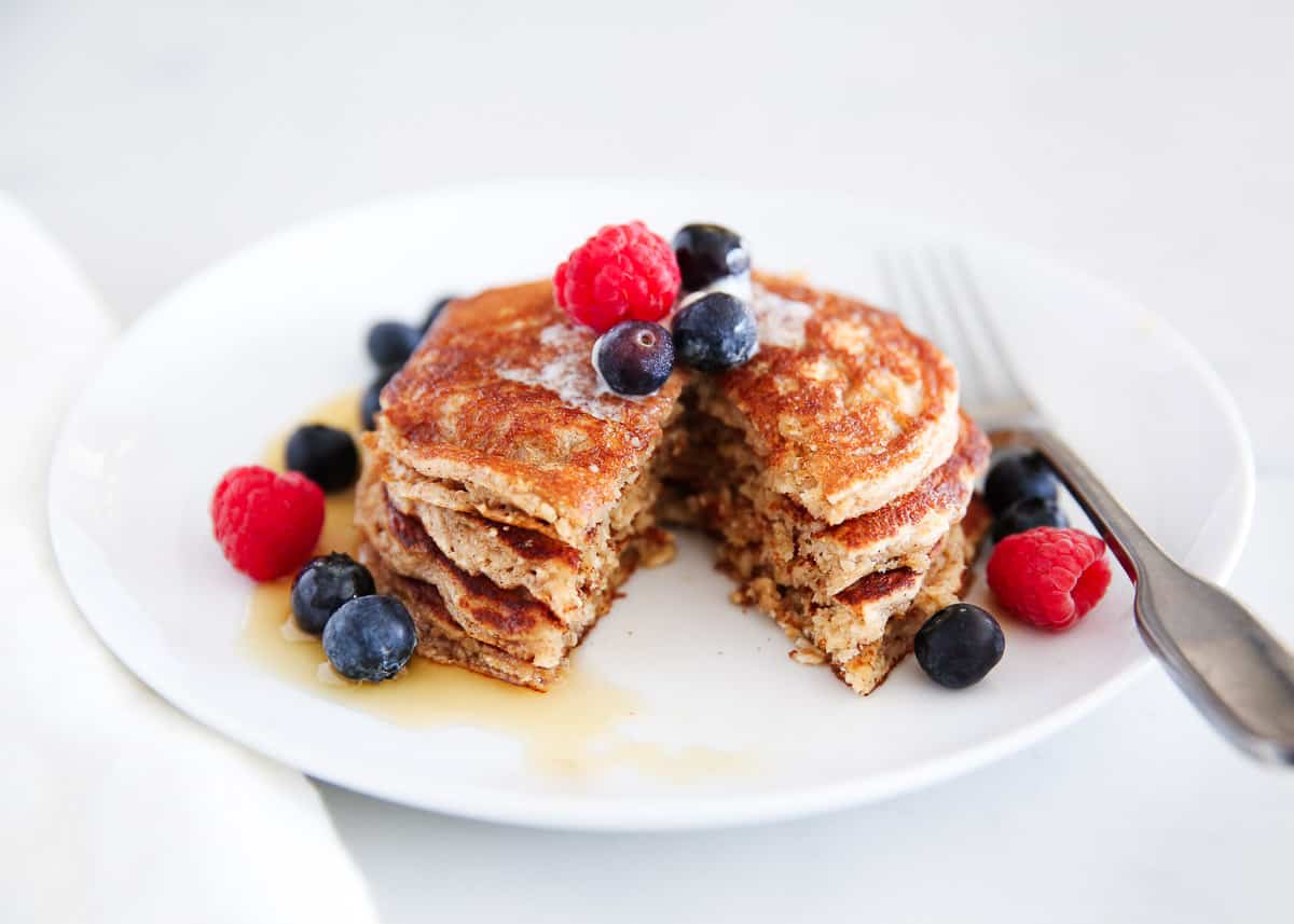 Oatmeal pancakes on a white plate with berries.