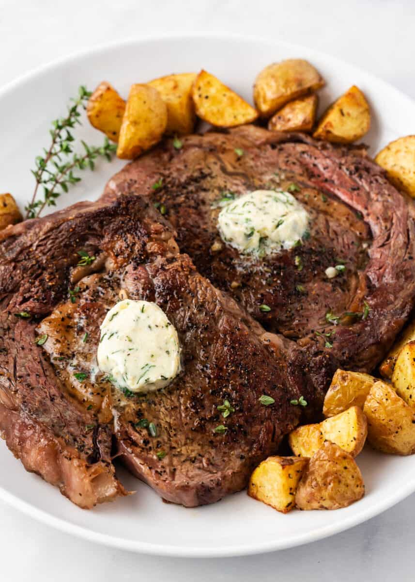 Cooked steak and potatoes on a white plate.