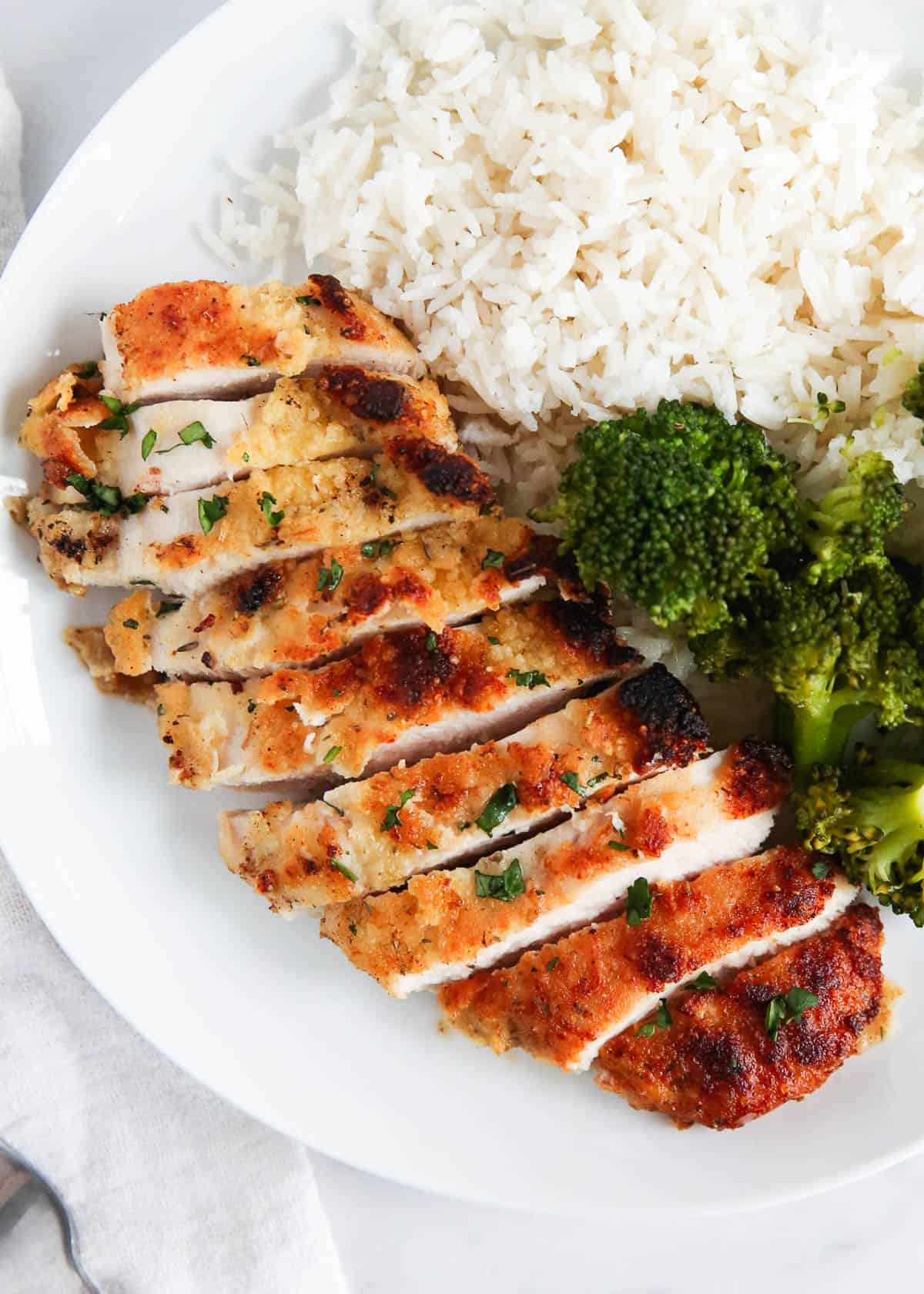 Parmesan crusted chicken sliced with rice and broccoli.