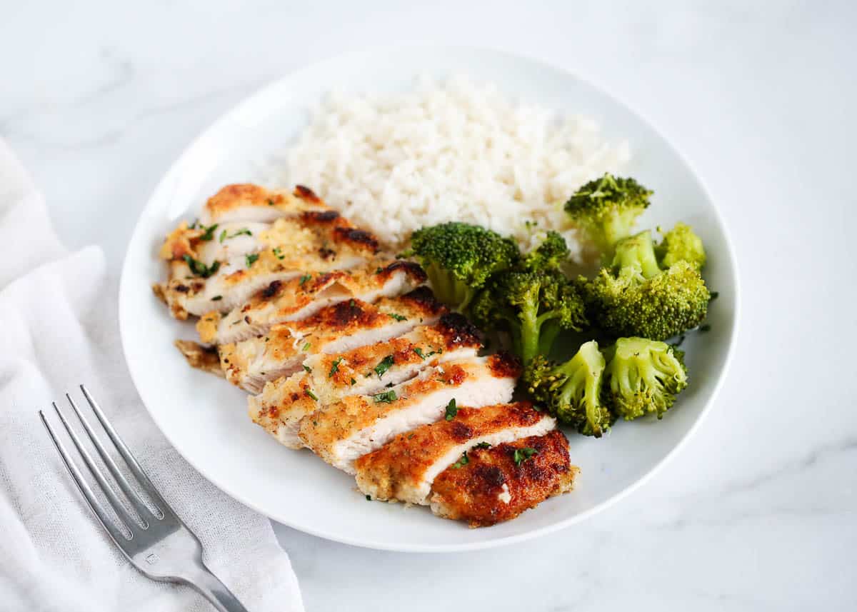 Parmesan crusted chicken and broccoli on a white plate.
