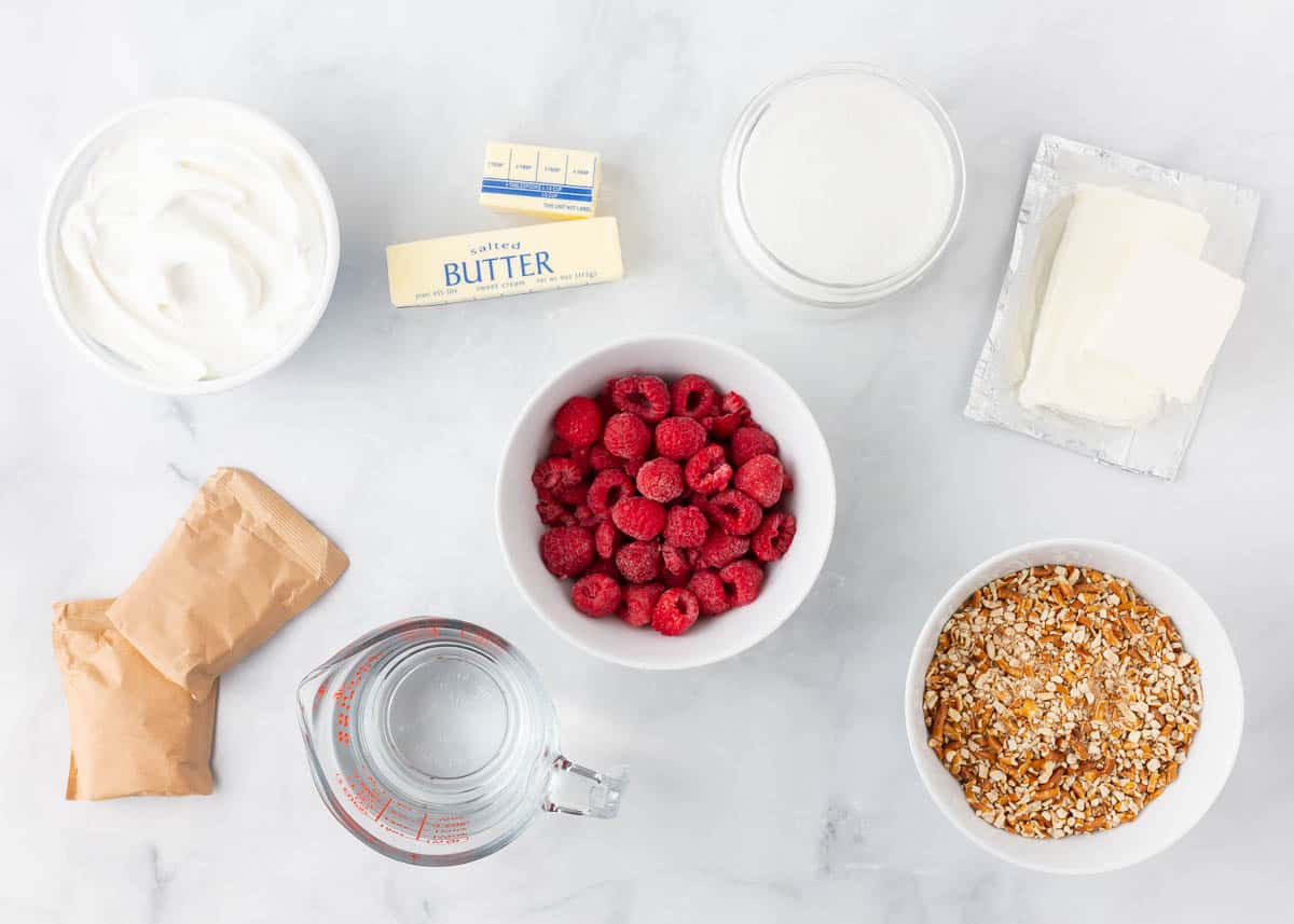 Raspberry jello pretzel salad ingredients on marble counter.