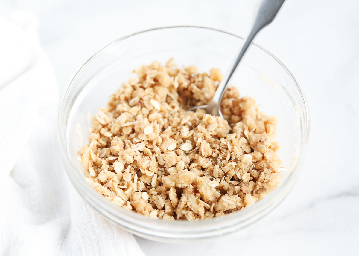 Streusel topping in a glass bowl with a metal spoon.