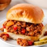 Turkey Sloppy Joe on a white plate with pickles.
