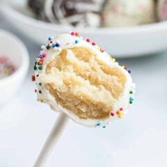 Homemade cake pop with a bite taken out showing moist vanilla cake interior dipped in white chocolate coating.