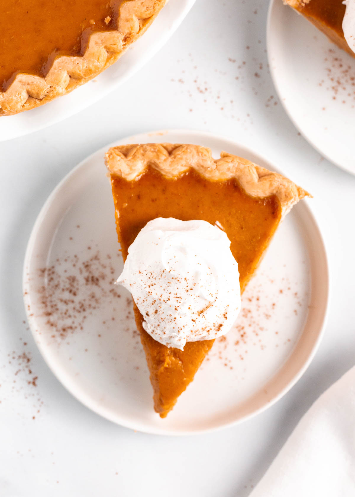 An overhead photo shot of a slice of pumpkin pie with whipped cream on top. 