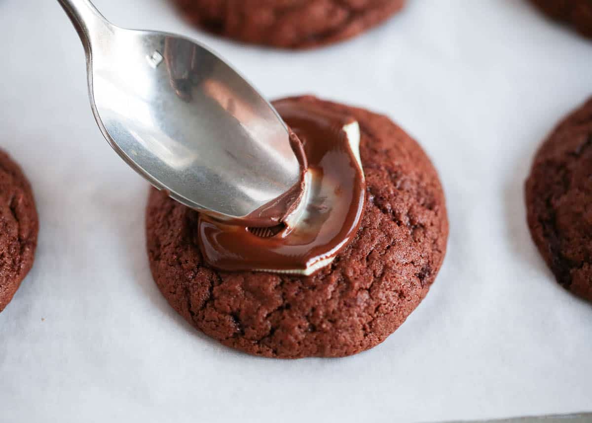 These Andes Mint cookies are made with an Andes mint melted on top of a soft-baked chocolate cookie! Sprinkle more mint chocolate chunks on top for an indulgent treat. Adding an Andes mint on top of a chocolate cookie.