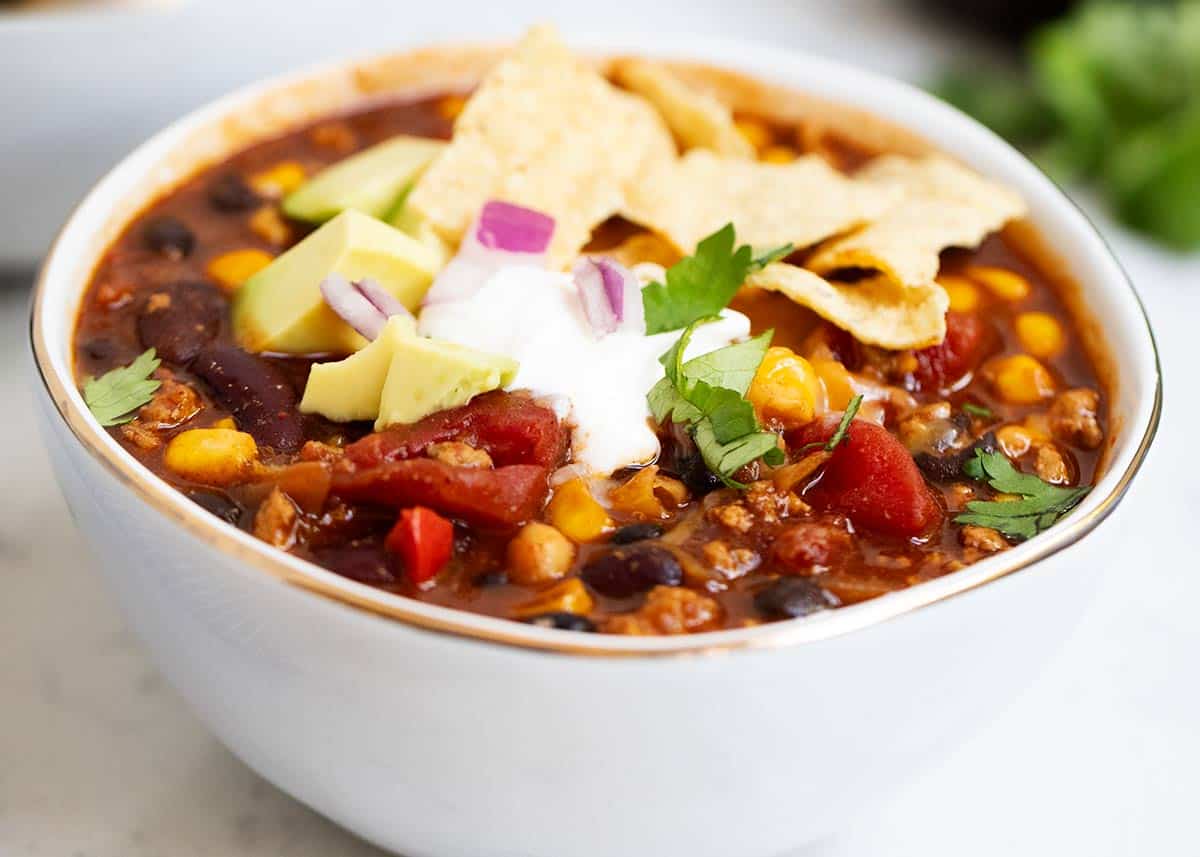 Turkey chili in a white bowl with toppings.