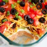 7 layer dip with layer of beans, sour cream, guacamole, cheese and tomatoes.