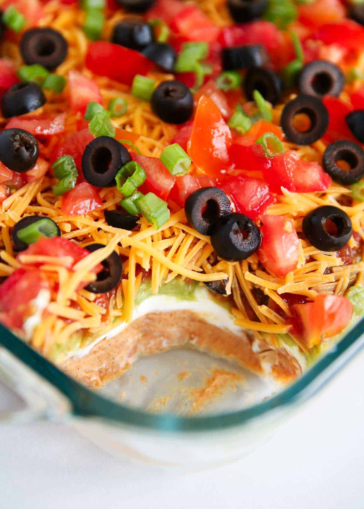 7 layer dip with layer of beans, sour cream, guacamole, cheese and tomatoes.