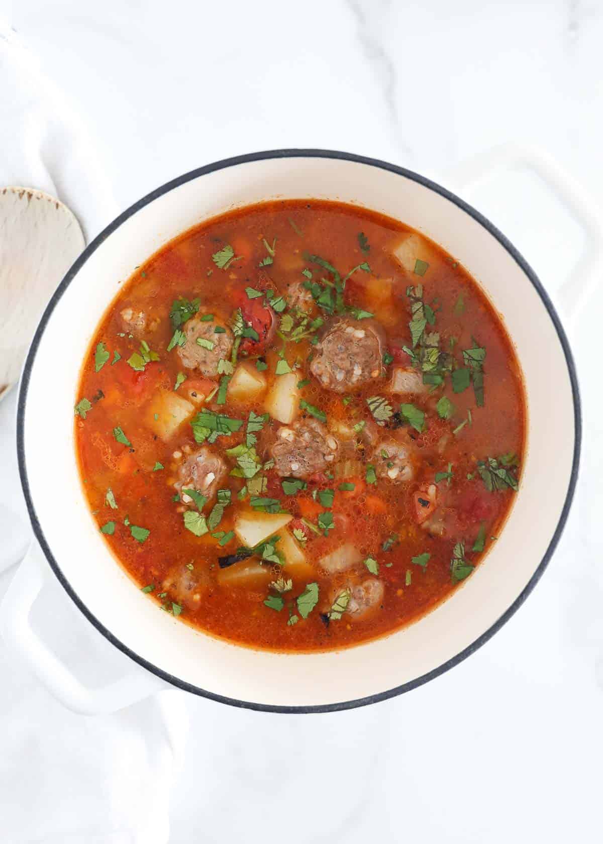 Albondigas soup in a white pot.