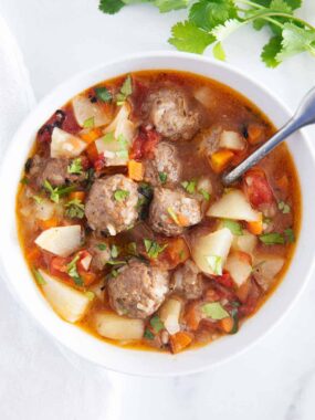 Albondigas soup in a white bowl.