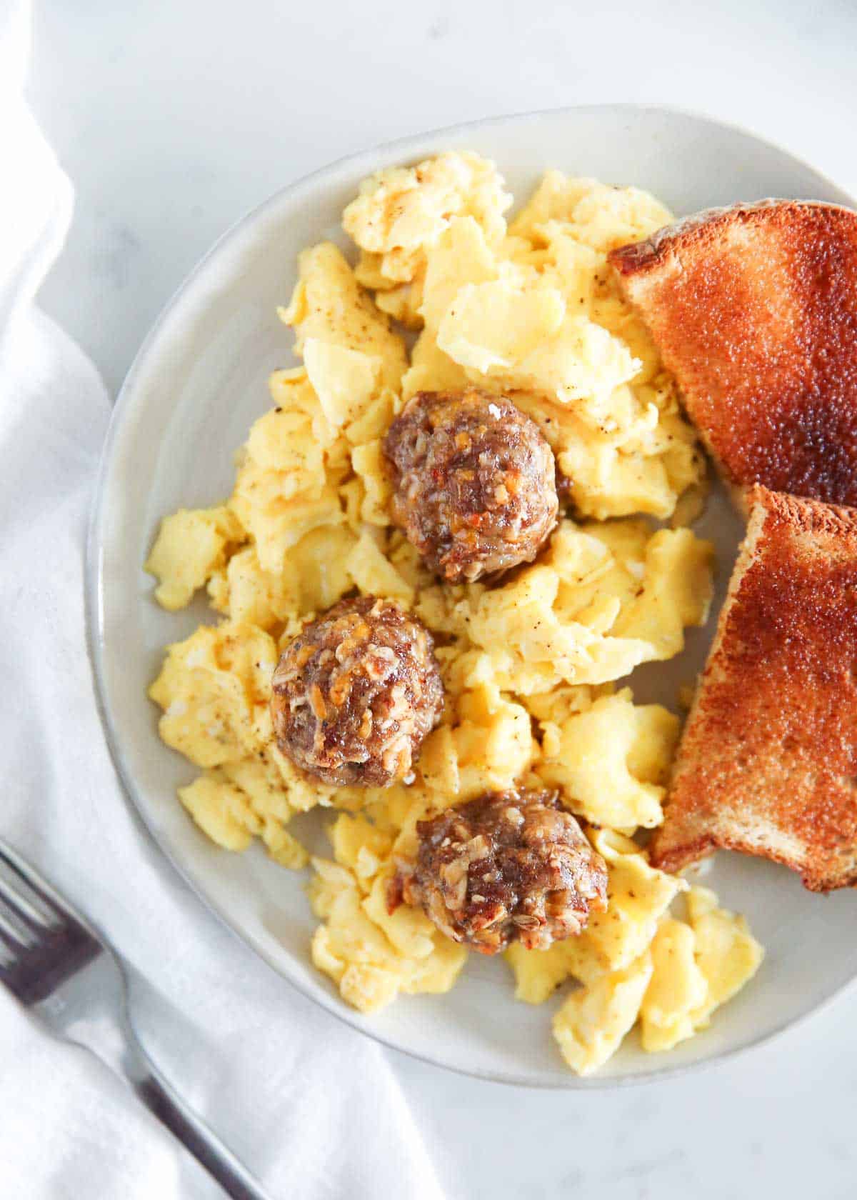 Scrambled eggs on a plate with breakfast meatballs.