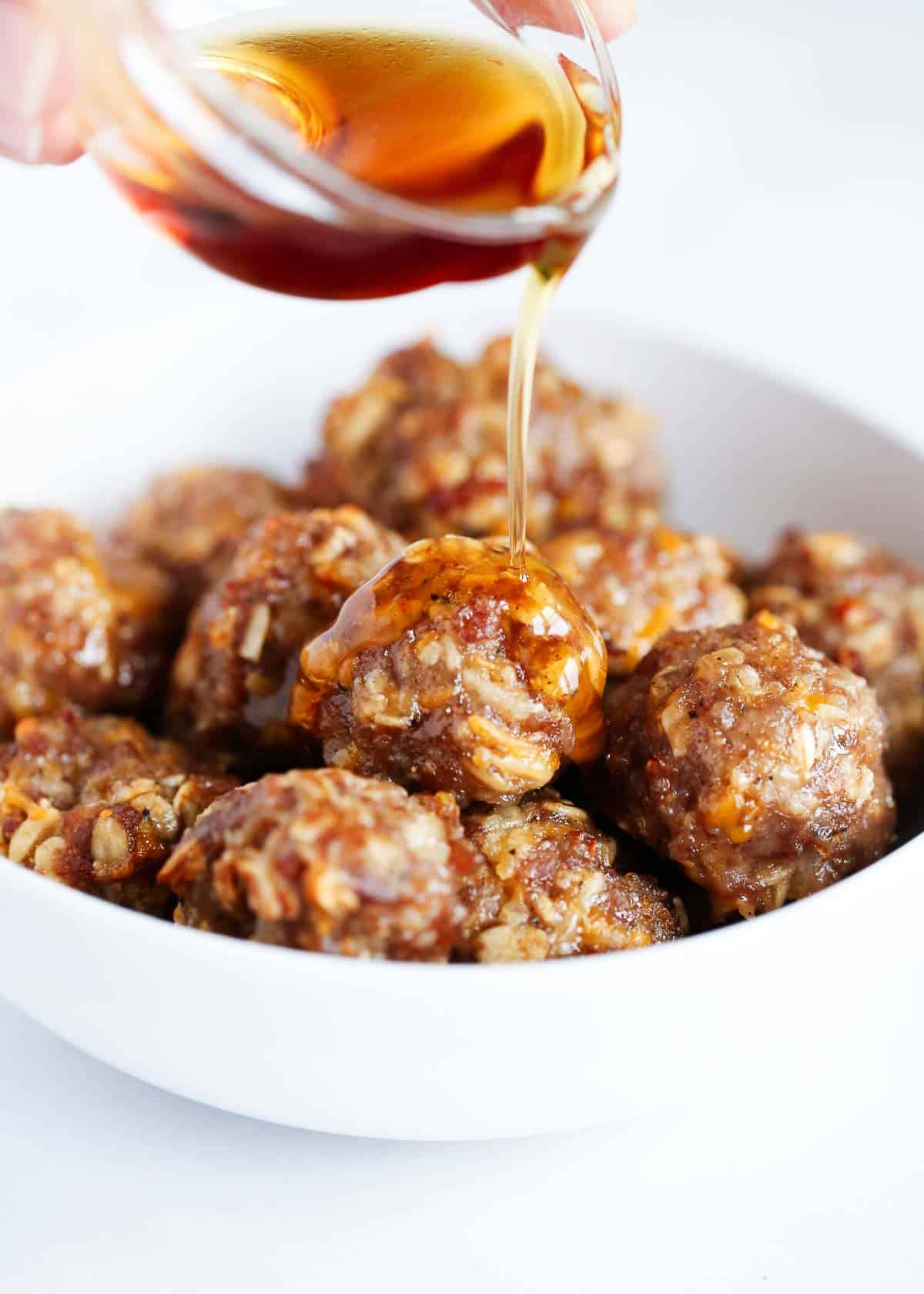 Pouring maple syrup on breakfast meatballs.