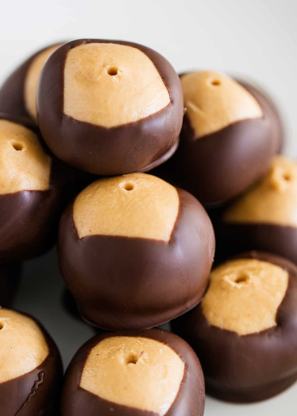 Buckeyes stacked on top of each other on a white plate.