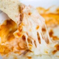 Buffalo chicken dip being dipped with a tortilla chip.
