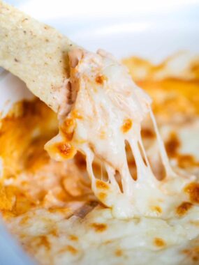 Buffalo chicken dip being dipped with a tortilla chip.