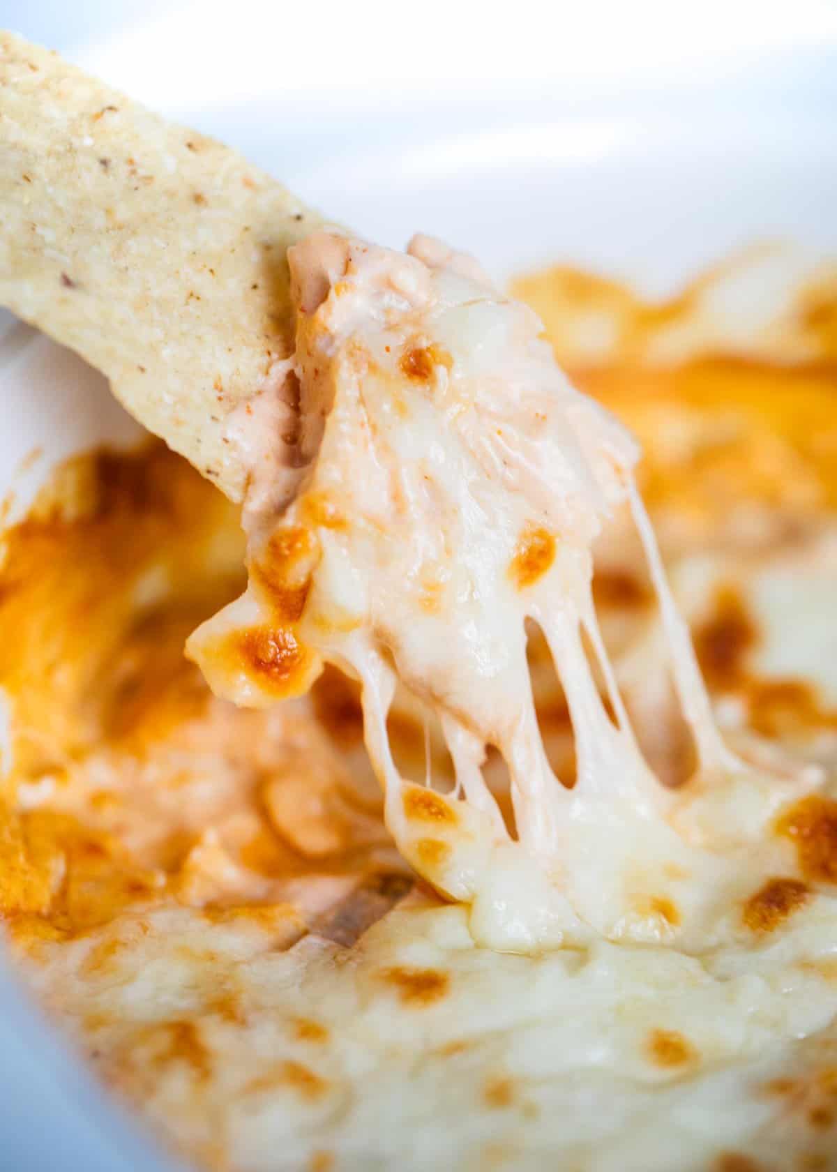 Buffalo chicken dip being dipped with a tortilla chip.