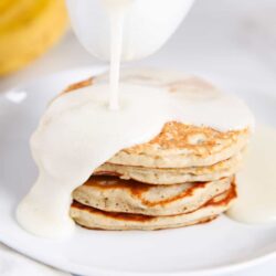 Pouring buttermilk syrup on top of pancakes.