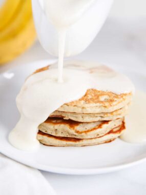 Pouring buttermilk syrup on top of pancakes.