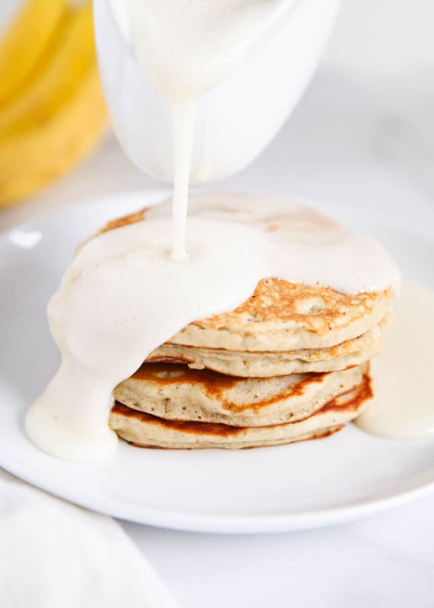 Pouring buttermilk syrup on top of pancakes.