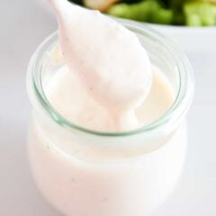 Caesar salad dressing in a jar with a spoon.