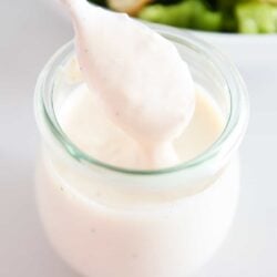 Caesar salad dressing in a jar with a spoon.