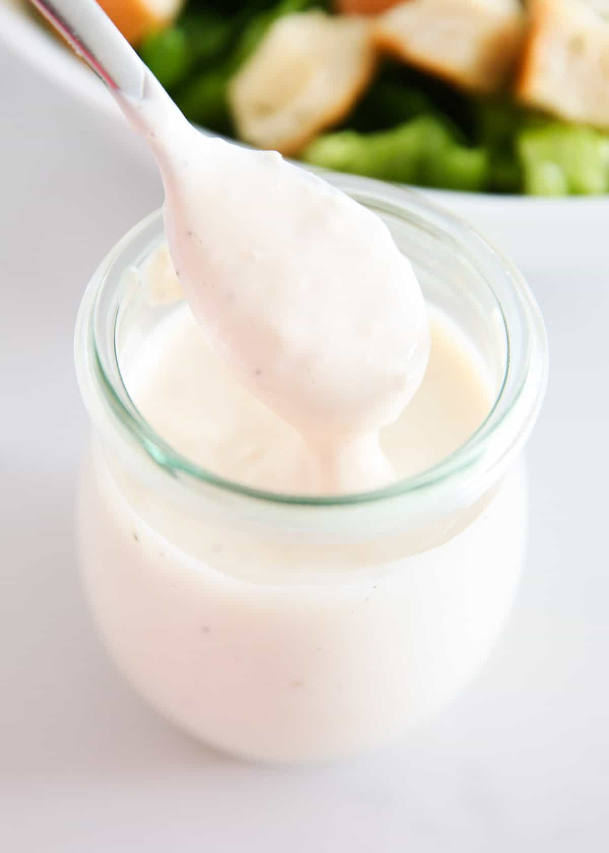 Caesar salad dressing in a jar with a spoon. 