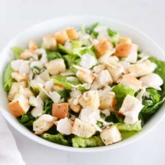 Caesar salad in a bowl with romaine, croutons and dressing.