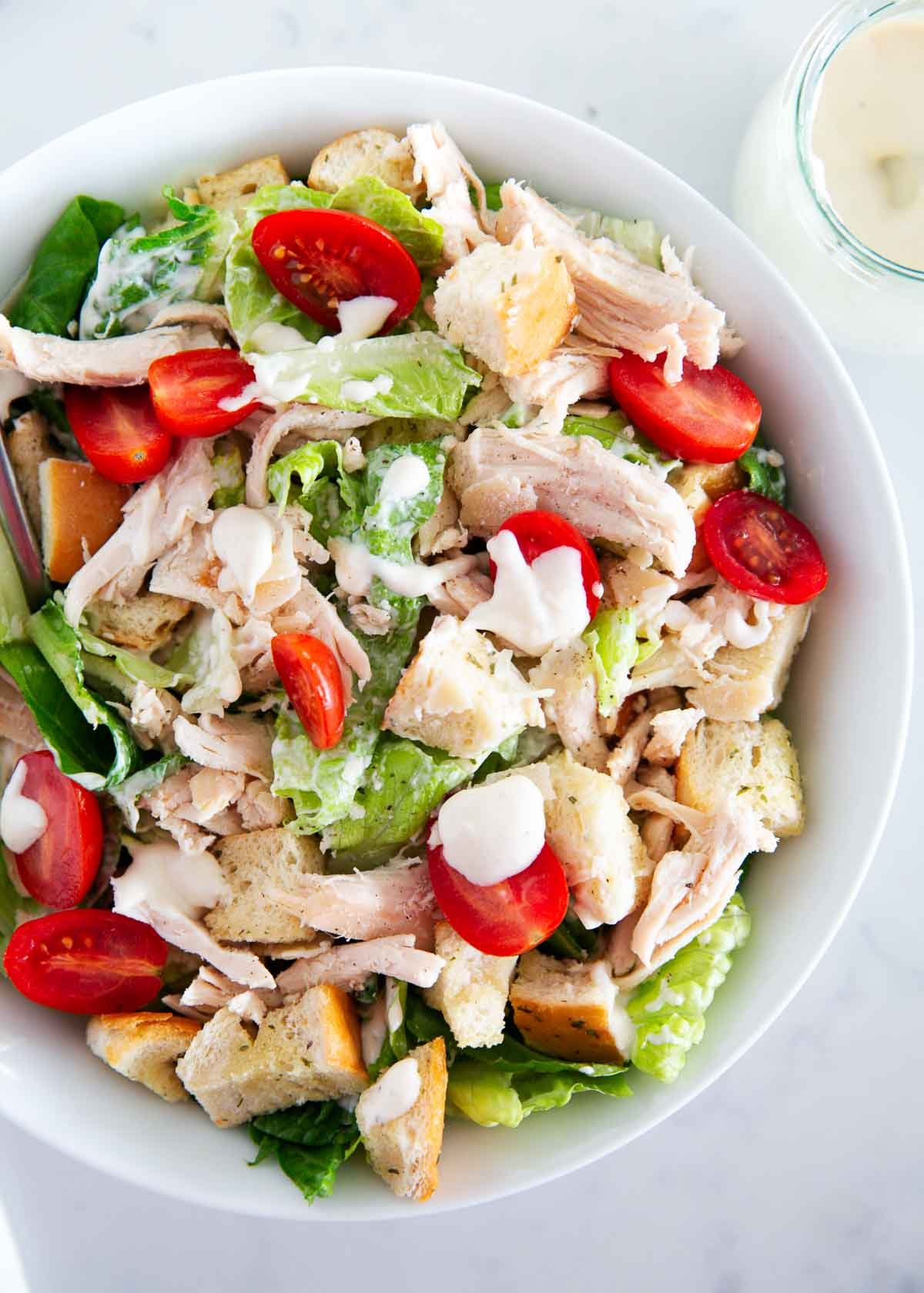 Caesar salad with chicken and tomatoes in a bowl.