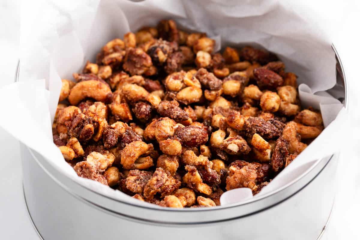 These easy and addictive mixed candied nuts make a fantastic holiday snack and/or seasonal gift that your friends and family will love! Candied nuts in a metal container.