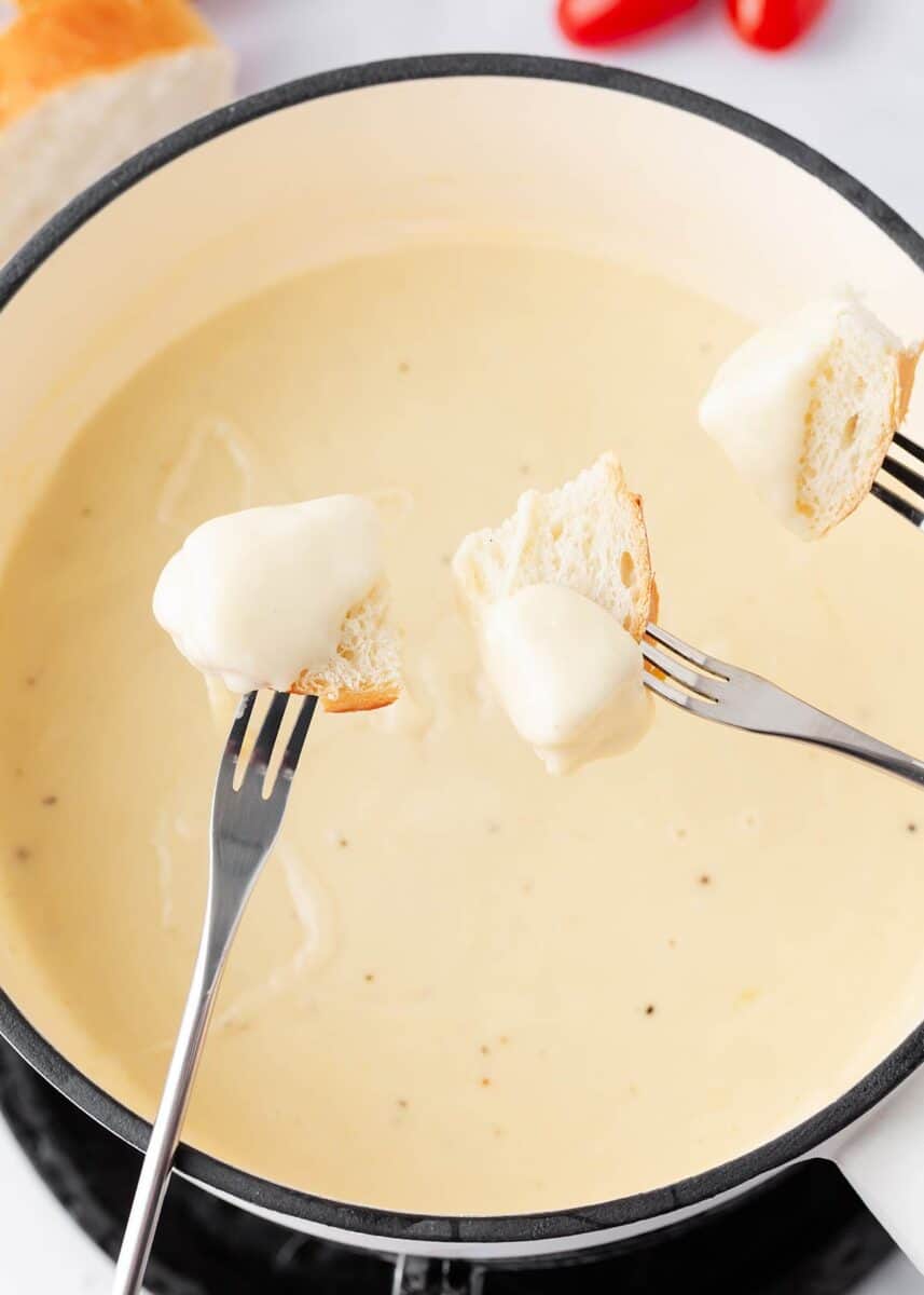 Forks dipping bread into a pot of cheese fondue.