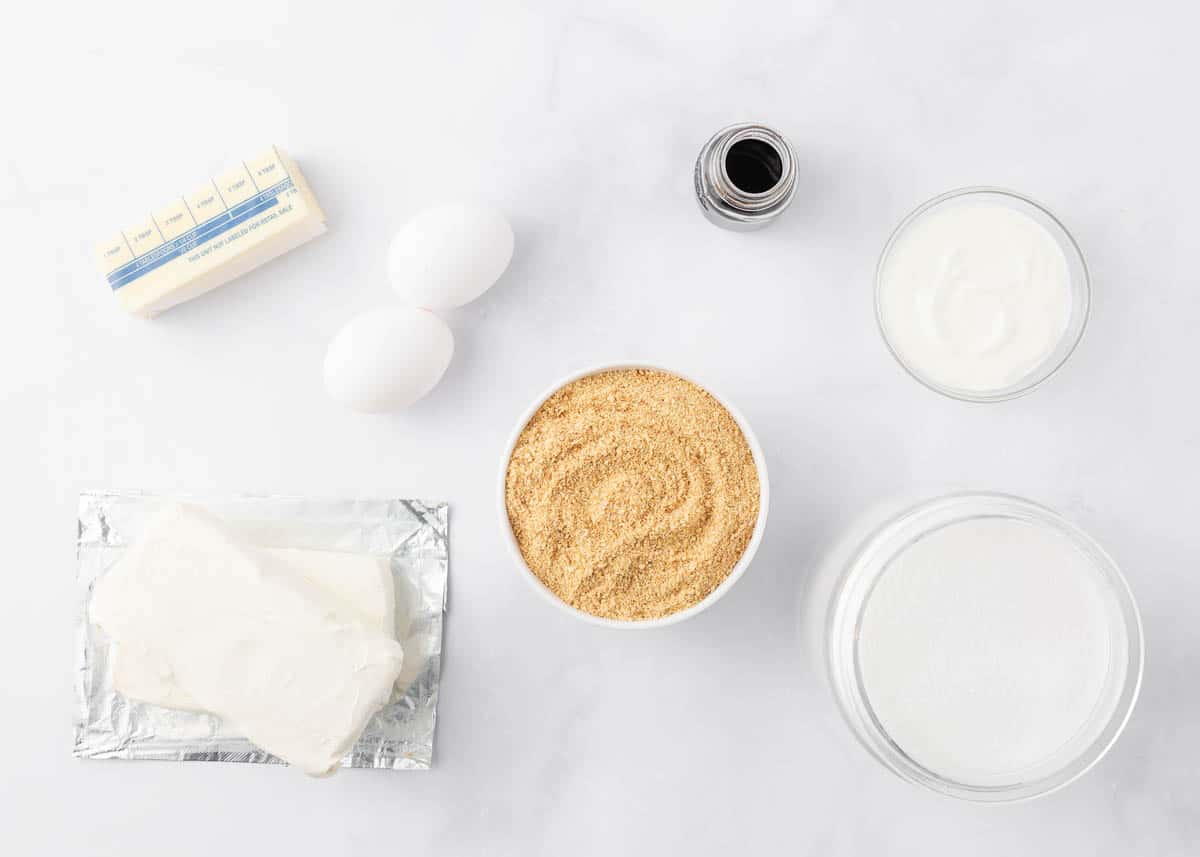 Cheesecake bars ingredients on marble counter.