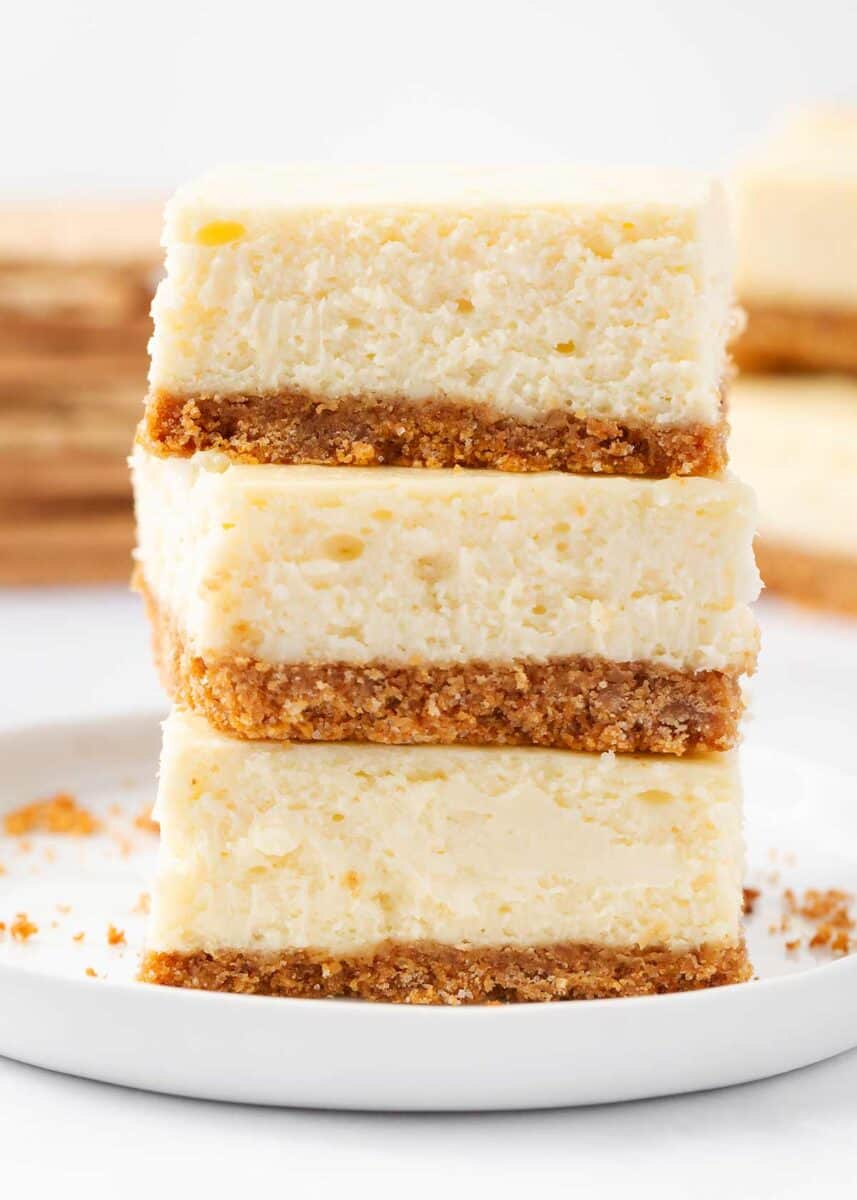 Stack of cheesecake bars on a white plate.