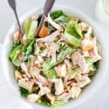 Chicken caesar salad in a white bowl.