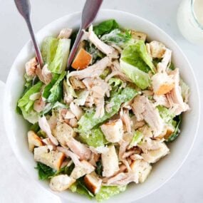 Chicken caesar salad in a white bowl.