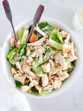 Chicken caesar salad in a white bowl.