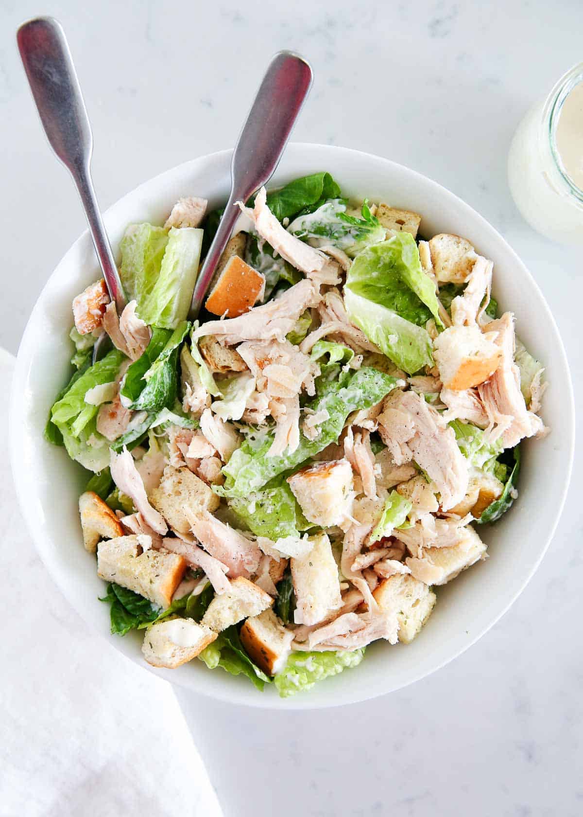 Chicken caesar salad in a white bowl.