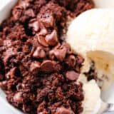Chocolate dump cake in a white bowl with ice cream.