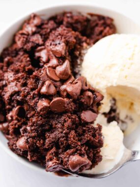 Chocolate dump cake in a white bowl with ice cream.