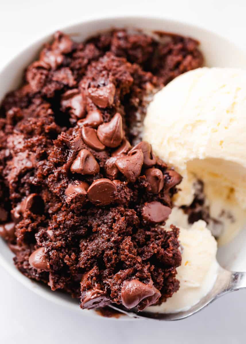 Chocolate dump cake in a white bowl with ice cream.
