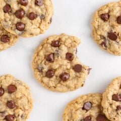 Oatmeal chocolate chip cookies with crisp edges and soft centers, with one cookie showing a bite.