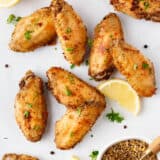 Lemon pepper wings with lemons on a platter.