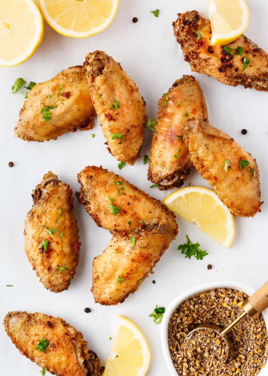 Lemon pepper wings with lemons on a platter.