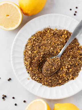 Lemon pepper seasoning in a white bowl with a spoon.