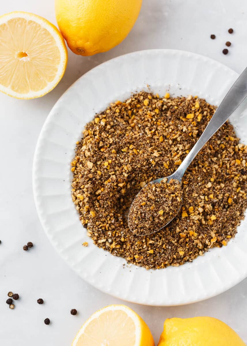 Lemon pepper seasoning in a white bowl with a spoon.