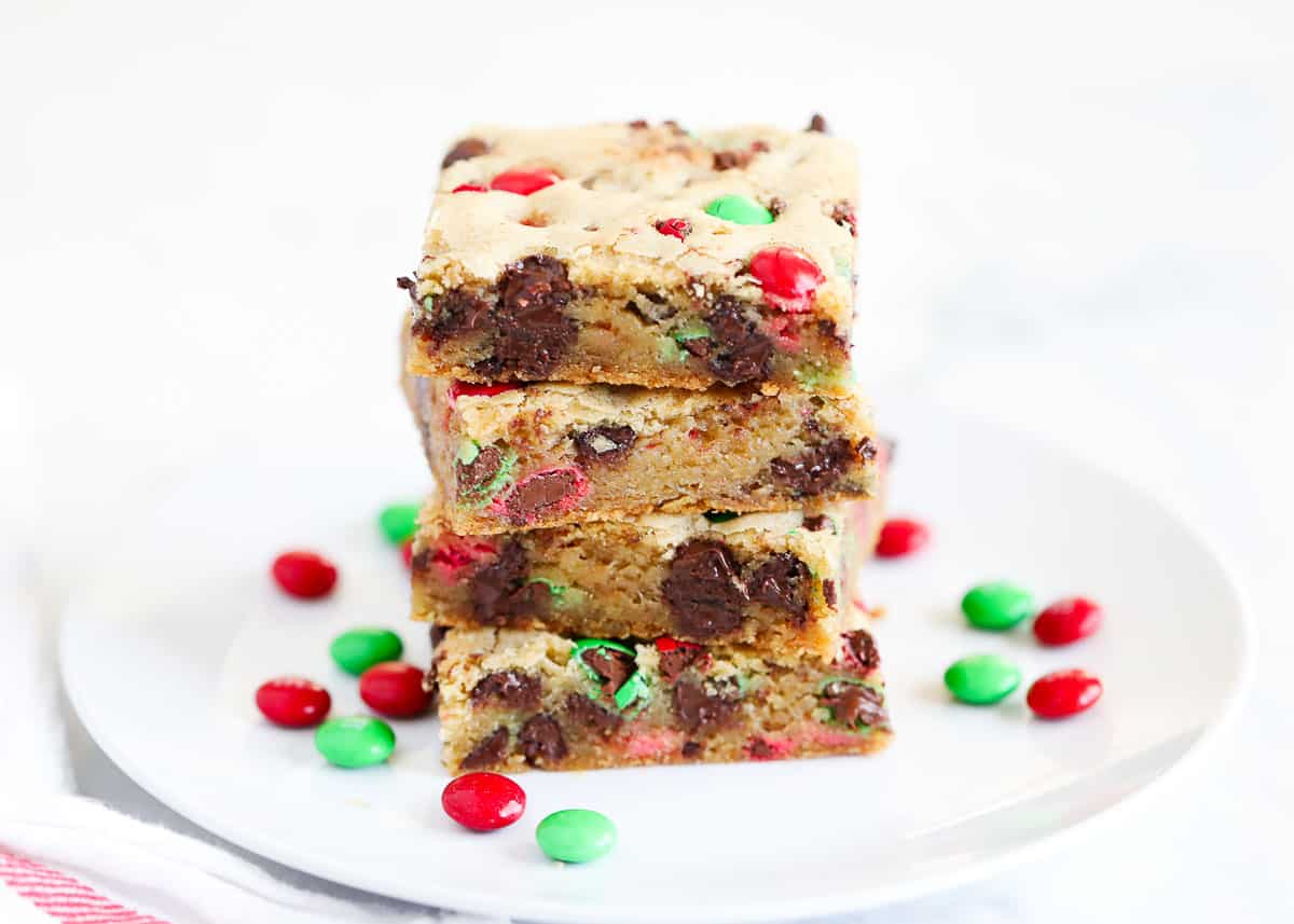 Stacked m&m cookie bars on a white plate.