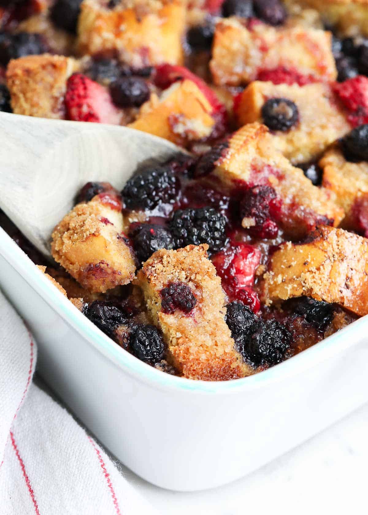 Overnight french toast casserole with a wooden spoon.