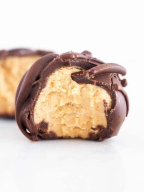 Creamy peanut butter ball coated in smooth chocolate with the inside texture visible after a bite.