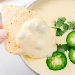 Dipping a tortilla chip in a bowl of queso blanco.